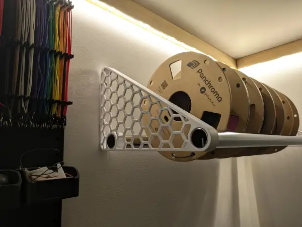 A white honeycomb filament spool rack mounted on a workshop wall